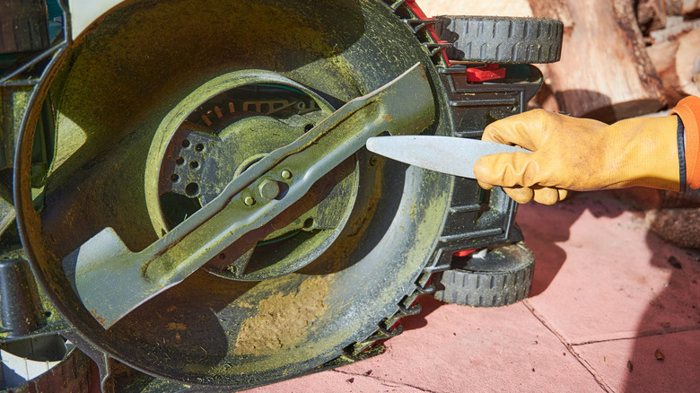 A man sharpens a lawn mower blade.